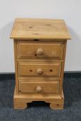 A pine three drawer bedside chest