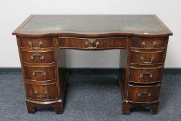 A mahogany serpentine fronted twin pedestal writing desk with green tooled leather inset panel