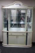 A cream high gloss four door display cabinet fitted cupboards and drawer beneath