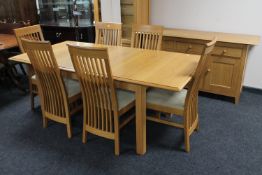 A contemporary oak pull out dining table together with a set of six rail back chairs