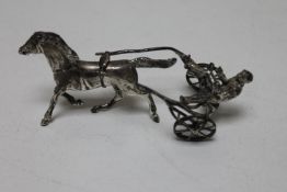 A white metal figure of a racer with horse,