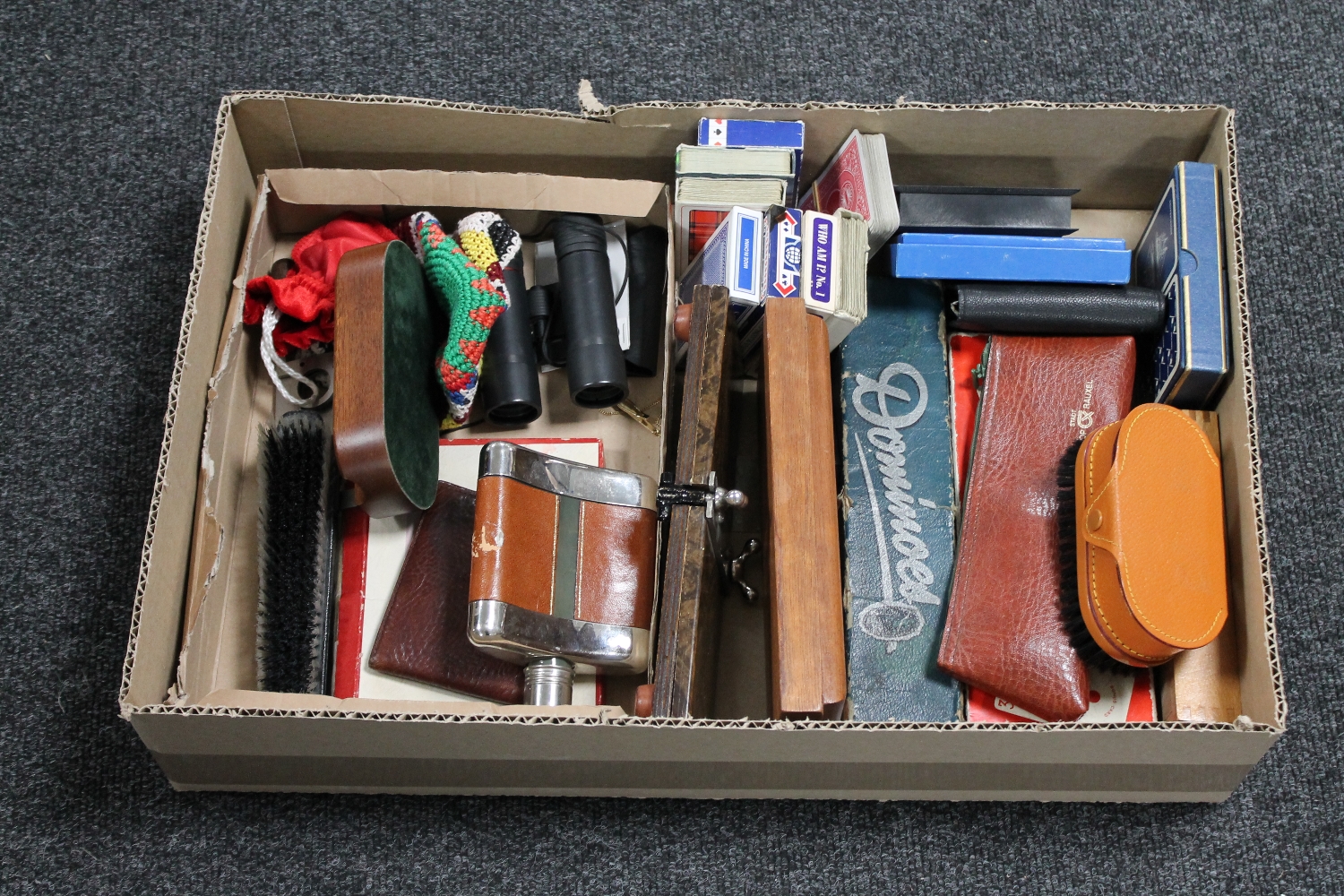 A box of tie presses, playing cards, dominoes, hip flask, binoculars,