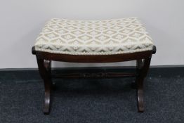 A mahogany dressing table stool on X-frame support upholstered in gold and cream fabric