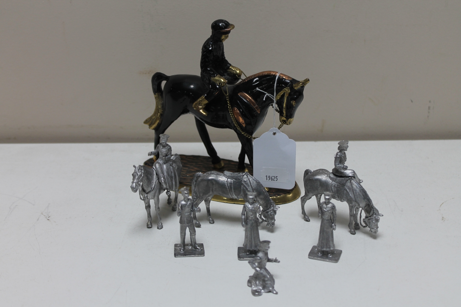A painted brass and copper figure of a jockey on horseback together with seven further unpainted