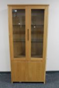 A contemporary oak double door glazed display cabinet fitted cupboard beneath