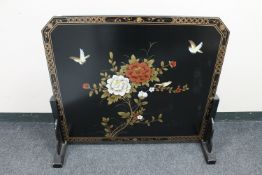 An oriental style black lacquered fire screen decorated with flowers and birds