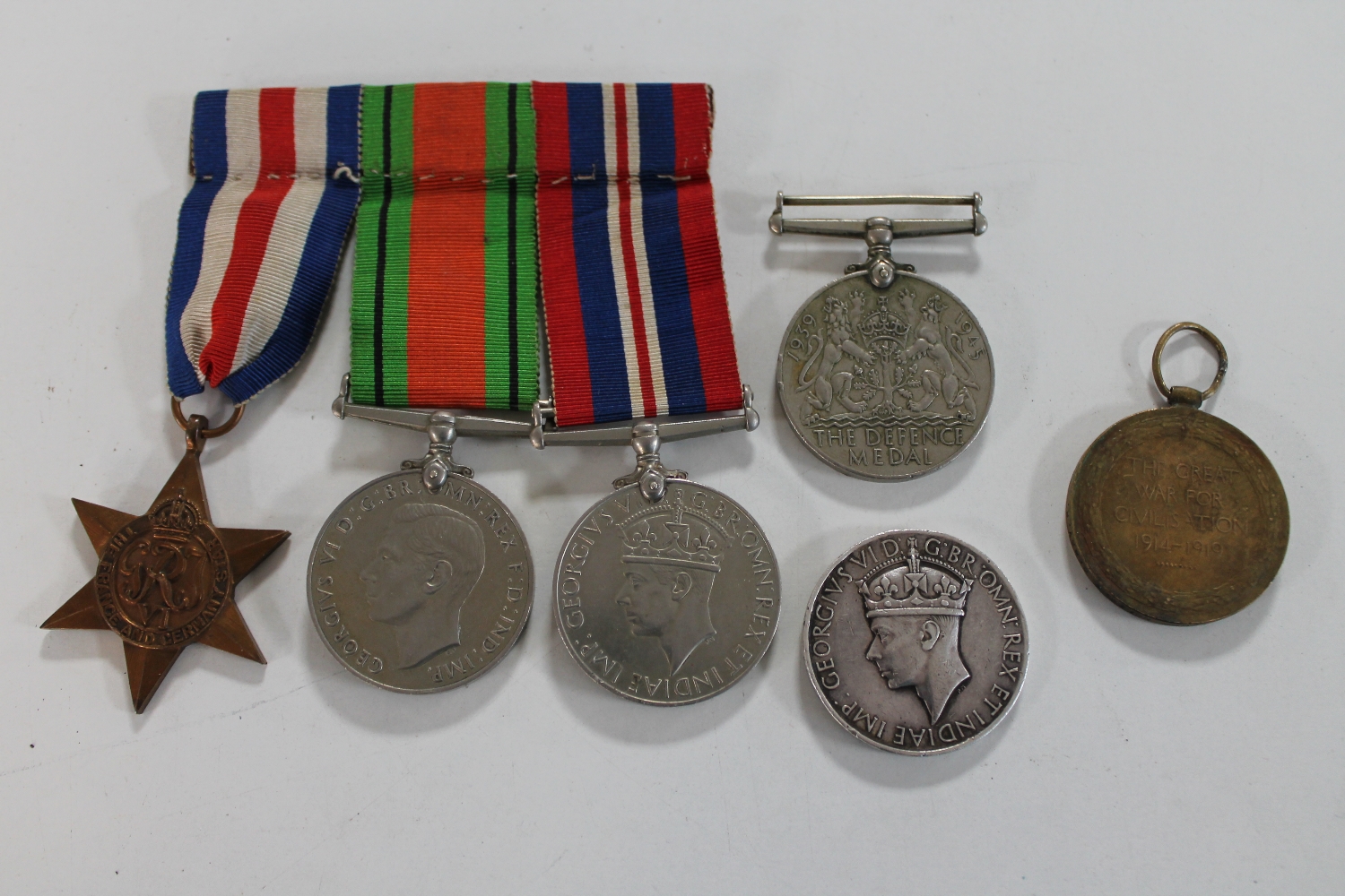 A trio of WWII Defence medals on bar with ribbons and a WWI awarded to Private J Newton, Knotts,