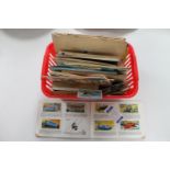 A basket of cigarette and tea card albums and loose tea cards