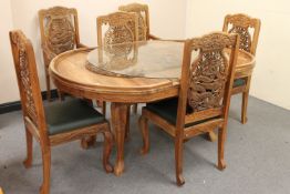 A profusely carved hardwood Indian extending dining table, together with six chairs,