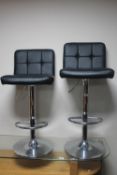 A pair of black leather adjustable bar stools