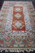 A fringed woollen carpet of Eastern design on peach ground