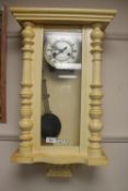 An early twentieth century painted wall clock with enamelled dial and pendulum