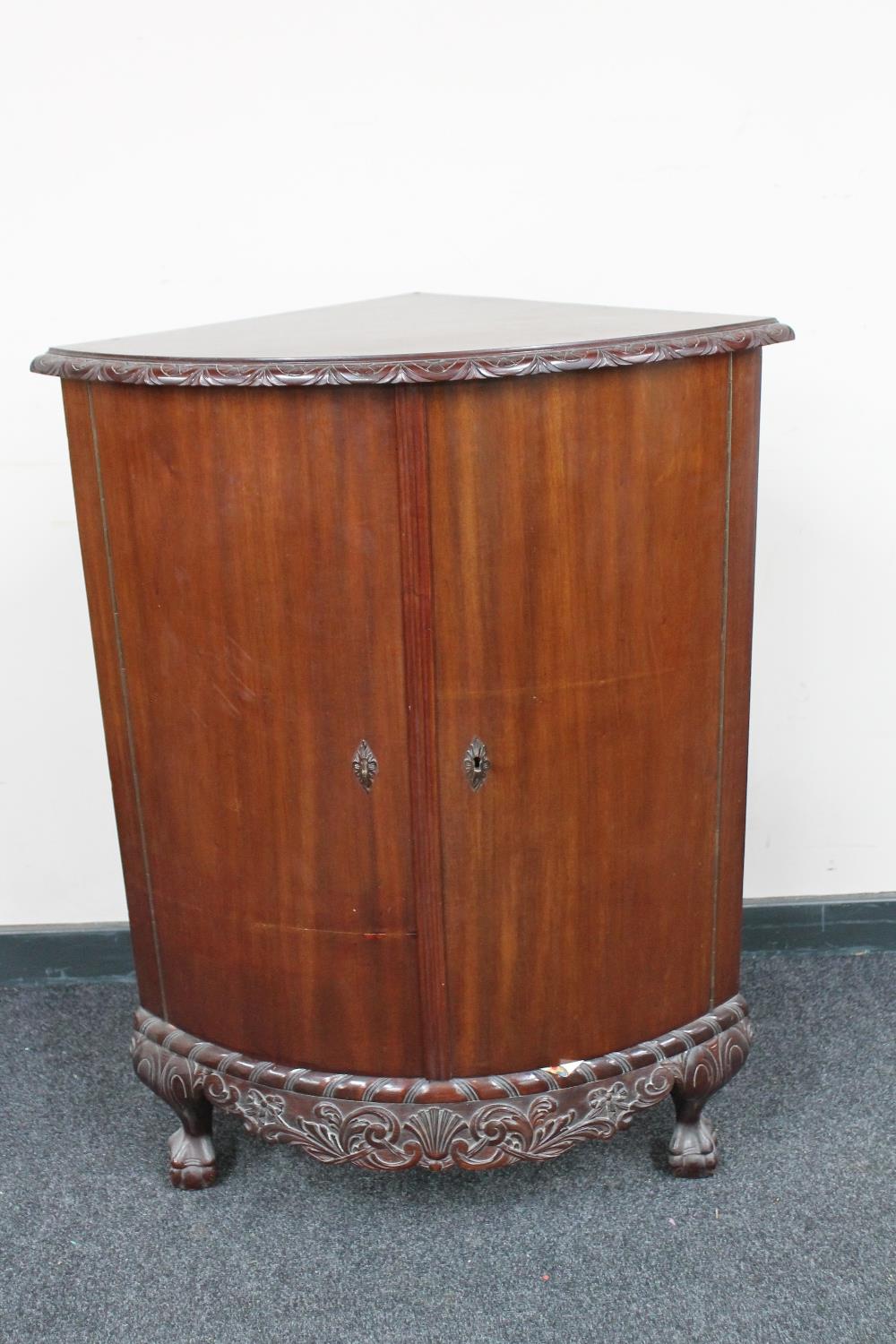 An antique mahogany corner cabinet on claw and ball feet