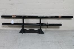 A pair of Japanese style swords in scabbards and a Japanese Katana on stand