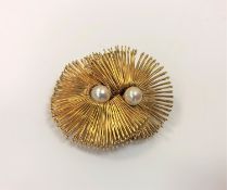 A yellow metal brooch set with two pearls.