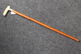 An early 20th century ivory handled walking stick with silver mounts, inscribed F.