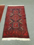 An Afghan Balouch rug on red ground 190 cm x 102 cm