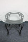 A contemporary circular glass topped lamp table on metal base