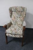 A wing backed armchair upholstered in floral fabric