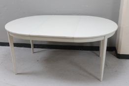 A circular white kitchen table with extension leaf