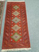 A Caucasian design rug on red ground 203 cm x 84 cm