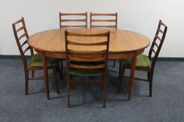 A mid twentieth century oval teak G-plan extending dining table and five ladder backed chairs