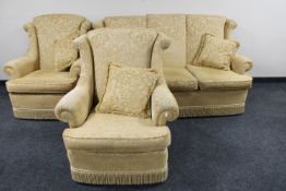 A three piece wing backed lounge suite in gold floral brocade