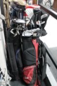 Three golf bags containing assorted irons and drivers