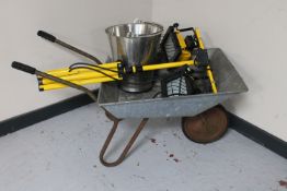 A wheel barrow containing an aluminium bucket and set of twin site lights on stand