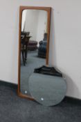 An early twentieth century circular frameless mirror together with a further teak framed hall