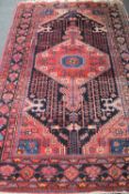 A Persian woollen rug of geometric design on red ground