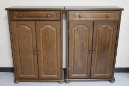 A pair of continental oak double door cabinets fitted with a drawer on bun feet