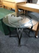 A circular wrought iron glass topped lamp table