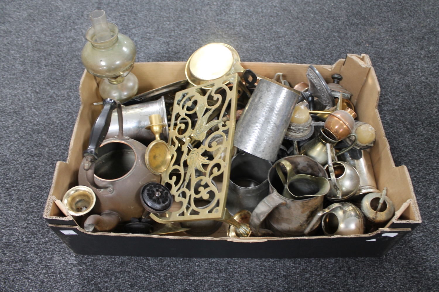 A box of antique metal ware including pewter tankard, brass footman, oil lamp,