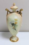 A Royal Worcester blush ivory hand painted lidded urn with gilded handles, height 23.