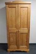 A pine double door hanging wardrobe fitted a shelf