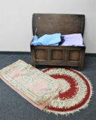 An oak blanket box containing two fringed Chinese rugs, bedding,