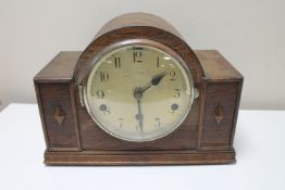 A 1930's oak cased mantel clock with silvered dial