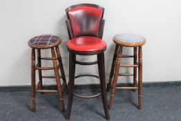 A contemporary oxblood leather bar chair and a pair of bar stools