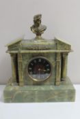 An antique onyx and brass mantel clock surmounted by a brass bust