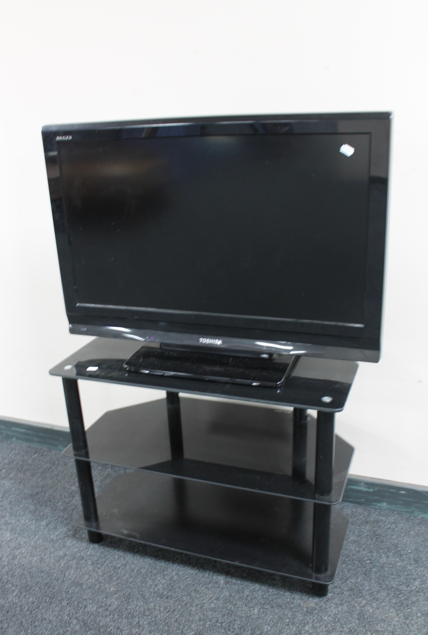 A Toshiba Regza 32" LCD TV with remote on three tier stand