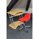 A computer desk and red plastic swivel chair