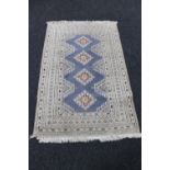 A fringed woollen rug of geometric design on cream ground