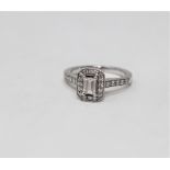 A platinum and diamond cluster ring, the central emerald cut stone weighing approximately 0.