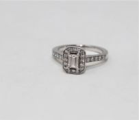 A platinum and diamond cluster ring, the central emerald cut stone weighing approximately 0.