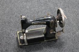 A vintage Gritzner sewing machine with tin of accessories