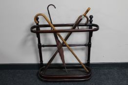 An antique Bentwood stick stand with metal tray containing three vintage walking sticks and a