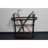 An antique Bentwood stick stand with metal tray containing three vintage walking sticks and a