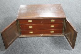 An antique mahogany double door cutlery cabinet fitted with three drawers and a small quantity of