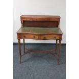 A mahogany serpentine fronted writing desk with three green leather inset panels with shelf above